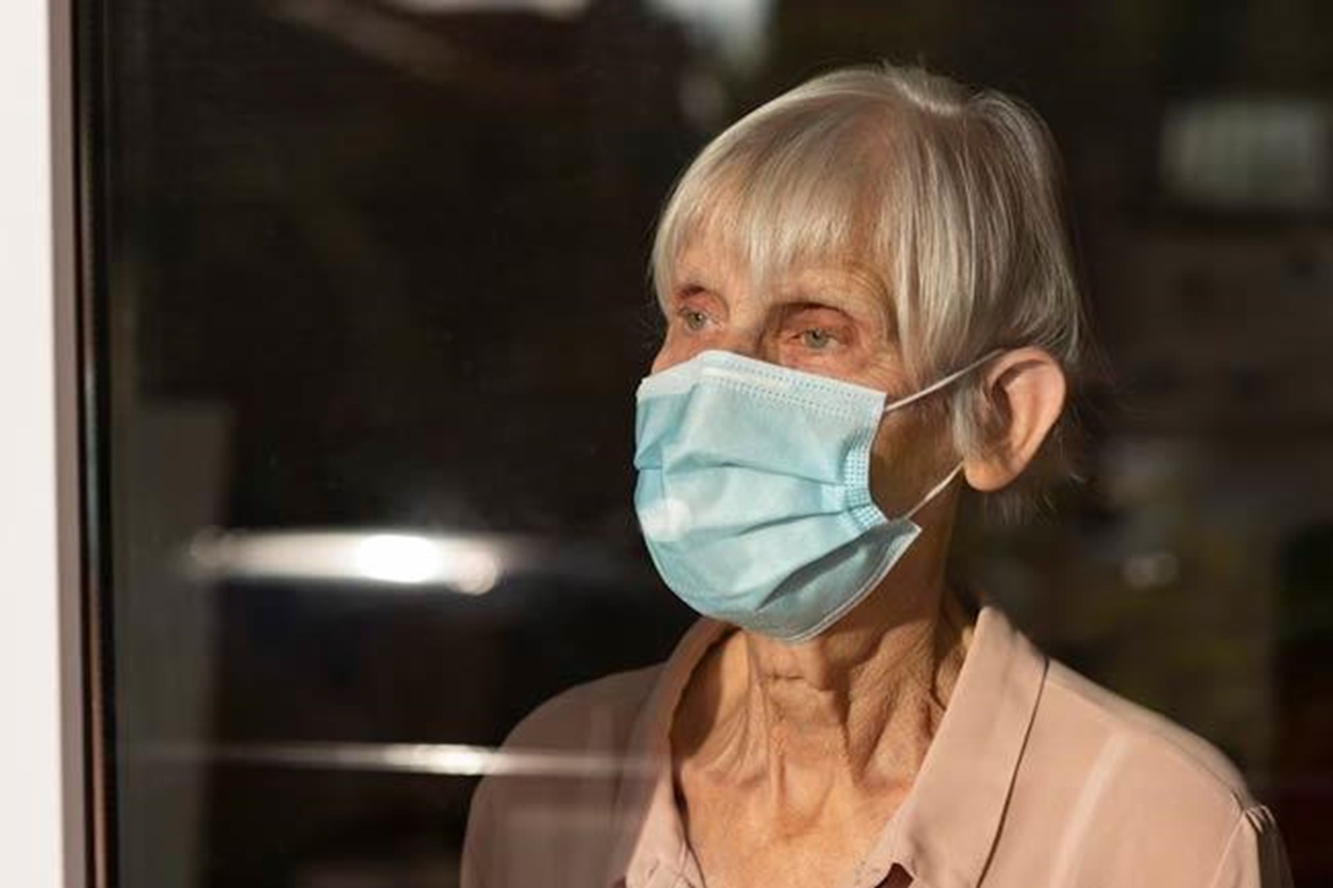 Einsame Seniorin hinter wartet hinter einem Fenster